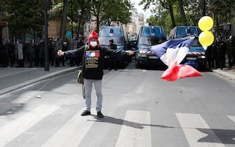 A protester waves a French flag and balloons in front of French gendarmes, during a demonstration in Paris, on July 14, 2020, as part of a nationwide day of protests by health workers to demand better work conditions. - Health care workers are protesting in France on the country's National day to demand more for their sector a day after the government and unions signed an agreement giving over eight billion euros in pay rises, with the prime minister admitting the move was overdue in view of the coronavirus pandemic. (Photo by Zakaria ABDELKAFI / AFP) (Photo by ZAKARIA ABDELKAFI/AFP via Getty Images)