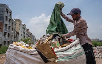 NEW DELHI, INDIA - JULY 14: An Indian ragpicker collects valuable waste items from a dumping site on July 14, 2020  in New Delhi, India.  With over 900,000 confirmed cases and 23,000 deaths, environmental and health experts have warned that India, which is currently the third worst COVID19-affected country, could face further challenges in tackling the impact of the global pandemic if immediate steps are not taken for the proper disposal of masks, gloves, personal protective equipment and other waste materials. (Photo by Yawar Nazir/Getty Images)