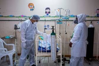 1225949416 Health personnel care for a child infected with COVID-19 at the Intensive Care ward of the Felipe Urriola Hospital in Iquitos, Peru on July 8, 2020. - Among the patients with COVID-19 in Peru are 24 children in the hospital in Iquitos, the largest city in the Peruvian Amazon, which was the first region in the country to feel the rigours of the pandemic. (Photo by Cesar Von BANCELS / AFP) (Photo by CESAR VON BANCELS/AFP via Getty Images)