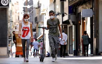 SPAIN PANDEMIC CORONAVIRUS COVID19 epa08549898 A couple wearing protective face masks take a stroll along downtown in Lleida, Catalonia, Spain, 16 July 2020. Regional authorities announced special movement restriction measures in the area of Segria in Lleida due to a coronavirus outbreak. EPA/Susanna Saez