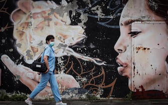 epa08549504 A paramedic walks past a graffiti while on her way to test residents for coronavirus disease (COVID-19) in the town of Tolosa, Basque Country, 16 July 2020. Residents are being tested for COVID-19 in the town after at least 22 positive cases were recorded so far.  EPA/JAVIER ETXEZARRETA