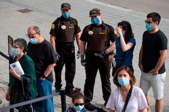 Security guards wearing face masks control visitors entering the Sagrada Familia basilica in Barcelona on July 4, 2020 as it reopens with a tribute to healthcare workers following a national lockdown to stop the spread of the novel coronavirus. (Photo by Josep LAGO / AFP) (Photo by JOSEP LAGO/AFP via Getty Images)