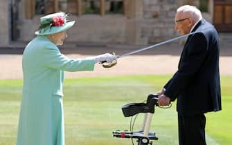 Britain's Queen Elizabeth II uses the sword that belonged to her father, George VI as she confers the Honour of Knighthood on 100-year-old WWII veteran Captain Tom Moore at Windsor Castle in Windsor, west of London on July 17, 2020. - British World War II veteran Captain Tom Moore was made a a Knight Bachelor (Knighthood) for raising over £32 million for the NHS during the coronavirus pandemic. (Photo by Chris Jackson / POOL / AFP) (Photo by CHRIS JACKSON/POOL/AFP via Getty Images)