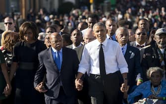 US President Barack Obama walks alongside Amelia Boynton Robinson (R), one of the original marchers, the Reverend Al Sharpton (2nd R), First Lady Michelle Obama (L), and US Representative John Lewis (2nd-L), Democrat of Georgia, and also one of the original marchers, across the Edmund Pettus Bridge to mark the 50th Anniversary of the Selma to Montgomery civil rights marches in Selma, Alabama, March 7, 2015. The event commemorates Bloody Sunday, when civil rights marchers attempting to walk to the Alabama capital of Montgomery to end voting discrimination against African Americans, clashed with police on the bridge. AFP PHOTO / SAUL LOEB        (Photo credit should read SAUL LOEB/AFP via Getty Images)