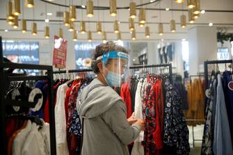 epa08556100 A woman wearing a face mask makes shopping on the Champs Elysee in Paris, France, 20 July 2020. From today, wearing a face mask inside closed public area becomes a duty in an attempt to stop the widespread of the SARS-CoV-2 coronavirus causing the Covid-19 disease.  EPA/YOAN VALAT