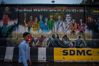NEW DELHI, INDIA - JULY 17: An Indian man wearing a mask walks in front of a mural  on July 17, 2020  in New Delhi, India. With the highest single-day surge of 34,956 cases, Indias confirmed Covid-19 infections crossed the 1 million mark as the worlds third worst hit country grapples to deal with the impact of the global epidemic. Even as death toll due to the deadly virus mounted to 25,602 with record 687 fatalities in a day, according to data released by the health ministry on early Friday, Indian Prime Minister Narendara Modi in a televised address said the country was ensuring one of the best recovery rates in the world in its fight against Covid-19. (Photo by Yawar Nazir/Getty Images)