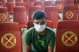 1222767079 TOPSHOT - A passenger sits next to signs requesting to maintain social distancing as a preventive measure against the spread of the COVID-19 coronavirus at the Hazrat Shahjalal International Airport in Dhaka on June 25, 2020. (Photo by MUNIR UZ ZAMAN / AFP) (Photo by MUNIR UZ ZAMAN/AFP via Getty Images)