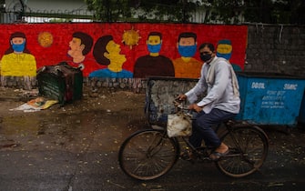 NEW DELHI, INDIA - JULY 17: An Indian cyclist paddles his bicycle in front a mural  on July 17, 2020  in New Delhi, India. With the highest single-day surge of 34,956 cases, Indias confirmed Covid-19 infections crossed the 1 million mark as the worlds third worst hit country grapples to deal with the impact of the global epidemic. Even as death toll due to the deadly virus mounted to 25,602 with record 687 fatalities in a day, according to data released by the health ministry on early Friday, Indian Prime Minister Narendara Modi in a televised address said the country was ensuring one of the best recovery rates in the world in its fight against Covid-19. (Photo by Yawar Nazir/Getty Images)