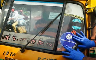 A police officer paste a sticker on the wind-screen of an auto-rickshaw as part of an awareness campaign to control the spread of the of the COVID-19 coronavirus, in Kolkata on July 20, 2020. - Coronavirus cases in India passed one million on July 17, official data showed as authorities struggle to check the spread of the deadly pandemic across the world's second-most populous nation. (Photo by Dibyangshu SARKAR / AFP) (Photo by DIBYANGSHU SARKAR/AFP via Getty Images)