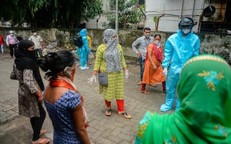 A volunteer health worker of the Non-Governmental Organization (NGO) Bharatiya Jain Sanghatana (BJS) wearing Personal Protective Equipment (PPE) using a smart helmet equipped with a thermo-scan sensor checks the body temperature of residents during a door-to-door medical screening drive for the COVID-19 coronavirus, at a residential area in Mumbai on July 21, 2020. - India on July 17 hit a million coronavirus cases, the third-highest total in the world, with no sign yet of the infection curve flattening as new cases emerge in rural areas. More than 25,000 people have died nationally. (Photo by INDRANIL MUKHERJEE / AFP) (Photo by INDRANIL MUKHERJEE/AFP via Getty Images)