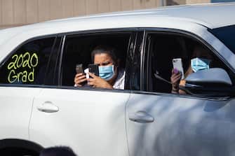 USA PANDEMIC CORONAVIRUS EDUCATION DRIVE THRU GRADUATION epa08557583 Family members of a graduate take pictures while wearing masks at a graduation ceremony at the California High School amid the coronavirus pandemic in Whittier, California, USA, 20 July 2020. Friends and family members were required to stay in their cars as the students were handed their diplomas by school staff who were social distancing and wearing masks, due to the coronavirus pandemic. EPA/CHRISTIAN MONTERROSA