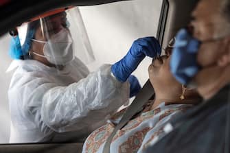 A laboratory worker takes a sample of a person at the Certus Lab's COVID-19 drive-thru test centre at the parking lot of the Caliente multipurpose complex in Tijuana, Baja California State, Mexico, on July 21, 2020 amid the novel coronavirus pandemic. - As Mexico's public health COVID-19 testing rate is one of the lowest worldwide, private laboratories running certified testing have become an option for people that can afford it. (Photo by Guillermo ARIAS / AFP) (Photo by GUILLERMO ARIAS/AFP via Getty Images)