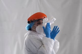 A laboratory worker wipes her face shield after taking a sample from a customer at the Certus Lab's COVID-19 drive-thru test centre at the parking lot of the Caliente multipurpose complex in Tijuana, Baja California State, Mexico, on July 21, 2020 amid the novel coronavirus pandemic. - As Mexico's public health COVID-19 testing rate is one of the lowest worldwide, private laboratories running certified testing have become an option for people that can afford it. (Photo by Guillermo ARIAS / AFP) (Photo by GUILLERMO ARIAS/AFP via Getty Images)