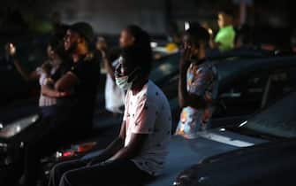 1216549720 Spectators watch sitting on the hood of their parked cars a stage play called Pidgin English "Grip am" (Hold it) at a drive-in theatre in Abuja on May 30, 2020 as lockdown restrictions to contain the outbreak of COVID-19 coronavirus are relaxed in the country. (Photo by Kola Sulaimon / AFP) (Photo by KOLA SULAIMON/AFP via Getty Images)