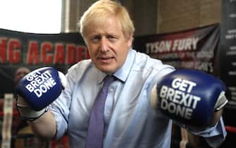 MANCHESTER, ENGLAND - NOVEMBER 19: Britain's Prime Minister Boris Johnson poses for a photo wearing boxing gloves emblazoned with "Get Brexit Done" during a stop in his General Election Campaign trail at Jimmy Egan's Boxing Academy on November 19, 2019 in Manchester, England. Britain goes to the polls on Dec.12. (Photo by Frank Augstein - WPA Pool/Getty Images)