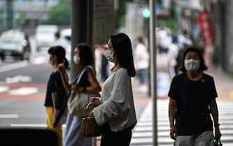 Face mask-clad pedestrians wait to cross a street in Tokyo on July 24, 2020. - Some 260 new cases COVID-19 coronavirus infections were recorded in the Japanese capital on July 24. (Photo by Charly TRIBALLEAU / AFP) (Photo by CHARLY TRIBALLEAU/AFP via Getty Images)