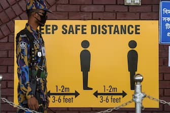 A security personnel stands next to a sign requesting to maintain social distancing as a preventive measure against the spread of the COVID-19 coronavirus at the Hazrat Shahjalal International Airport in Dhaka on June 25, 2020. (Photo by MUNIR UZ ZAMAN / AFP) (Photo by MUNIR UZ ZAMAN/AFP via Getty Images)