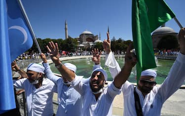 Men waves flags as people gather on July 24, 2020 outside Hagia Sophia in Istanbul to attend the Friday prayer, the first muslim prayer held at the landmark since it was reconverted to a mosque despite international condemnation. - A top Turkish court revoked the sixth-century monument's status as a museum on July 10 and Turkish President then ordered the building to reopen for Muslim worship. The UNESCO World Heritage site in historic Istanbul was first built as a cathedral in the Christian Byzantine Empire but was converted into a mosque after the Ottoman conquest of Constantinople in 1453. (Photo by OZAN KOSE / AFP) (Photo by OZAN KOSE/AFP via Getty Images)