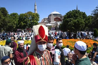 A man wearing a traditional Ottoman costume arrives with others on July 24, 2020 outside Hagia Sophia in Istanbul to attend the Friday prayer, the first muslim prayer held at the landmark since it was reconverted to a mosque despite international condemnation. - A top Turkish court revoked the sixth-century monument's status as a museum on July 10 and Turkish President then ordered the building to reopen for Muslim worship. The UNESCO World Heritage site in historic Istanbul was first built as a cathedral in the Christian Byzantine Empire but was converted into a mosque after the Ottoman conquest of Constantinople in 1453. (Photo by OZAN KOSE / AFP) (Photo by OZAN KOSE/AFP via Getty Images)