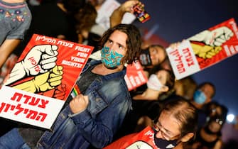 Israeli protesters, wearing protective face masks due to the coronavirus pandemic, hold placards as they take part in a demonstration against the Israeli Prime Minister Benjamin Netanyahu in the coastal city of Tel Aviv on July 25, 2020. - Public confidence in the government has been dented by a recent wave of contradictory emergency decrees opening, closing and reopening amenities, such as restaurants, public beaches and gyms. 
Protests against economic fallout from the coronavirus pandemic have spread across the country. (Photo by JACK GUEZ / AFP) (Photo by JACK GUEZ/AFP via Getty Images)
