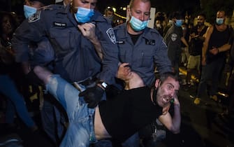 JERUSALEM, ISRAEL - JULY 25: Police officers detain a protester during a demonstration on July 25, 2020 in Jerusalem, Israel. Over several weeks, thousands of protesters have taken to the streets of the capital to protest about the government's handling of the coronavirus outbreak, as the country suffers a second wave of infections. Israeli Prime Minister Benjamin Netanyahu is also facing criticism for staying in office whilst facing corruption charges.  (Photo by Amir Levy/Getty Images)