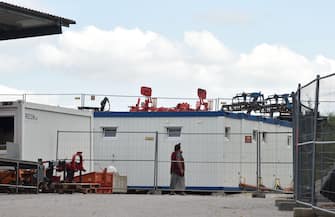 1227787924 A woman in quarantine walks in front of containers at the farm near the small Bavarian village of Mamming where an outbreak of COVID-10 coronavirus cases has raised, on July 26, 2020. - A total of 174 seasonal workers on a large Bavarian farm in the municipality of Mamming have tested positive for the coronavisrus COVID-19 and some 500 are in quarantine to contain a mass coronavirus outbreak. (Photo by Christof STACHE / AFP) (Photo by CHRISTOF STACHE/AFP via Getty Images)