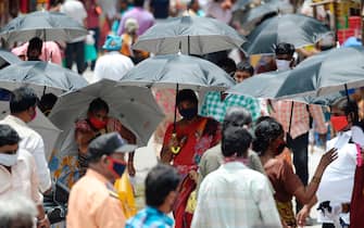 TOPSHOT - People hold umbrellas distributed by volunteers to maintain social distancing as a preventive measure against the COVID-19 coronavirus, in a market in Chennai on July 27, 2020. (Photo by Arun SANKAR / AFP) (Photo by ARUN SANKAR/AFP via Getty Images)