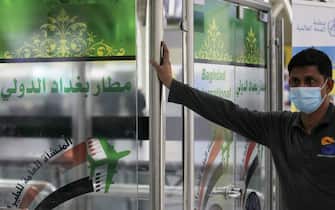 A worker wearing a protective mask stands at a gate marked "Baghdad International Airport" in Arabic at the departure hall of the Iraqi capital' sairport following its reopening on July 23, 2020, after a closure since March forced by the coronavirus pandemic restrictions, aimed at preventing the spread of the deadly COVID-19 illness in Iraq. (Photo by AHMAD AL-RUBAYE / AFP) (Photo by AHMAD AL-RUBAYE/AFP via Getty Images)