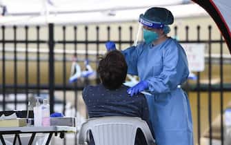 1263273413 SYDNEY, AUSTRALIA - AUGUST 02: A healthcare worker wearing a face shield and protective clothing tests a man for COVID-19 at a pop-up testing clinic in Rushcutters Bay on August 02, 2020 in Sydney, Australia. As Sydney COVID-19 clusters in the east, inner west and south west continue to grow, Sydney is on high alert with a further 12 cases of COVID-19 reported overnight in New South Wales. (Photo by James D. Morgan/Getty Images)