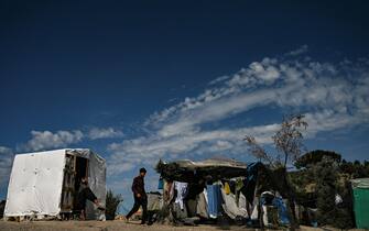 1221951169 A boy walks in a improvised tents camp near the refugee camp of Moria in the island of Lesbos on June 21, 2020. - Greece's announcement that it was extending the coronavirus lockdown at its migrant camps until July 5, cancelling plans to lift the measures on June 22, coincided with World Refugee Day on June 27, 2020. (Photo by ARIS MESSINIS / AFP) (Photo by ARIS MESSINIS/AFP via Getty Images)