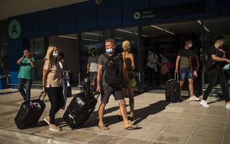 1223719280 Passengers of a flight from Budapest wearing protective face masks arrive at the Corfu Airport Ioannis Kapodistrias on Corfu Island on July 1, 2020, on its reopening day following months of closure due to the sanitary measures taken to curb the spread of the Covid-19 disease caused by the novel coronavirus. - Greece on July 1, 2020 reopened flights to its flagship island destinations as it raced to salvage a portion of the annual tourism season that is vital to its economy. (Photo by ANGELOS TZORTZINIS / AFP) (Photo by ANGELOS TZORTZINIS/AFP via Getty Images)