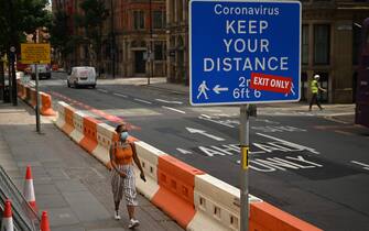 1227855186 A woman wears a facemask as she walks in the centre of Manchester, northwest England, on July 31, 2020. - Britain on Friday "put the brakes on" easing lockdown measures and imposed new rules on millions of households in northern England, following concerns over a spike in coronavirus infections. (Photo by Oli SCARFF / AFP) (Photo by OLI SCARFF/AFP via Getty Images)