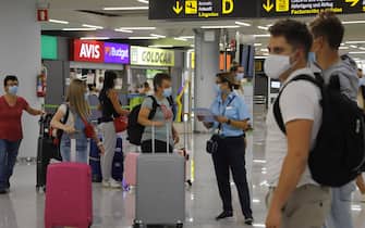 1262630674 MALLORCA, SPAIN - JULY 30: TUI workers speak to passengers at arrivals in Palma de Mallorca airport on July 30, 2020 in Mallorca, Spain. The United Kingdom, whose citizens comprise the largest share of foreign tourists in Spain, added Mallorca and other Spanish islands to its advice against non-essential travel to the country, citing a rise in coronavirus cases. The change follows the UK's decision to reimpose a 14-day isolation period for travelers returning from Spain. (Photo by Clara Margais/Getty Images)