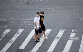 NEW YORK, NEW YORK - AUGUST 01: Two men wearing masks look at something while walking in a crosswalk as the city continues Phase 4 of re-opening following restrictions imposed to slow the spread of coronavirus on August 01, 2020 in New York City. The fourth phase allows outdoor arts and entertainment, sporting events without fans and media production. (Photo by Alexi Rosenfeld/Getty Images)