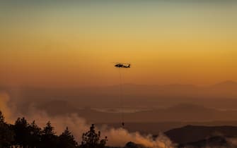 CHERRY VALLEY, CA - AUGUST 01: A helicopter drops water on the Apple Fire as an excessive heat warning continues on August 1, 2020 in Cherry Valley, California. The fire began shortly before 5 p.m. the previous evening, threatening a large number of homes overnight and forcing thousands to flee before exploding to 12,000 acres this afternoon, mostly climbing the steep wilderness slopes of the San Bernardino Mountains.  (Photo by David McNew/Getty Images)