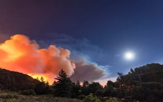 CHERRY VALLEY, CA - AUGUST 01: Flames approach on a western front of the Apple Fire, consuming brush and forest under a nearly full moon during an excessive heat warning on August 1, 2020 in Cherry Valley, California. The fire began shortly before 5 p.m. the previous evening, threatening a large number of homes overnight and forcing thousands to flee before exploding to 12,000 acres this afternoon, mostly climbing the steep wilderness slopes of the San Bernardino Mountains.  (Photo by David McNew/Getty Images)