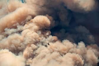 A firefighting airplane flies away from a pyrocumulus ash plume after making a retardant drop on a ridge as firefighters continue to battle the Apple fire near Banning, California on August 1, 2020. - 4,125 acres have burn in Cherry Valley, about 2,000 people have received evacuation orders in the afternoon of August 1. (Photo by JOSH EDELSON / AFP) (Photo by JOSH EDELSON/AFP via Getty Images)