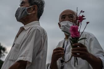HIROSHIMA, JAPAN - AUGUST 06: A man holds a flower as he queues to pray in remembrance on the 75th anniversary of the Hiroshima atomic bombing, on August 6, 2020 in Hiroshima, Japan. In a ceremony that has been scaled back significantly because of Covid-19 coronavirus, Japan will mark the 75th anniversary of the first atomic bomb that was dropped by the United States on Hiroshima on August 6, 1945. The bomb instantly killed an estimated 70,000 people and thousands more in coming years from radiation effects. Three days later the United States dropped a second atomic bomb on Nagasaki which ended World War II. (Photo by Carl Court/Getty Images)