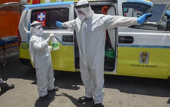 Health workers disinfect themselves before transferring a patient to Medellin's General Hospital, amid the COVID-19 pandemic, in Medellin on August 3, 2020. (Photo by JOAQUIN SARMIENTO / AFP) (Photo by JOAQUIN SARMIENTO/AFP via Getty Images)