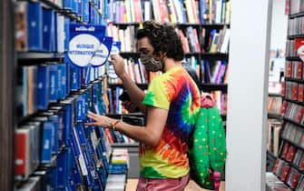 1227705682 A customer wearing a face mask looks at CDs in a multimedia store on July 20, 2020, in Paris, on the first day of compulsory mask-wearing in enclosed public spaces in France in a bid to prevent a second wave of COVID-19 (novel coronavirus) infections. - As officials noted signs of an uptick in virus circulation, people in France will risk a fine of 135 euros (154 USD) starting on July 20 for failure to comply with a new decree to wear a mask in public places indoors, the government announced. (Photo by ALAIN JOCARD / AFP) (Photo by ALAIN JOCARD/AFP via Getty Images)