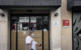 A woman wearing a protective mask passes by  a closed hotel on August 6, 2020 in Paris, amid the crisis linked with the Covid-19 pandemic caused by the novel coronavirus. (Photo by ALAIN JOCARD / AFP) (Photo by ALAIN JOCARD/AFP via Getty Images)