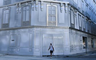A man wearing a protective mask passes by a scaffolding by Dior on August 7, 2020 in Paris, amid the crisis linked with the covid-19 pandemic caused by the novel coronavirus. (Photo by ALAIN JOCARD / AFP) (Photo by ALAIN JOCARD/AFP via Getty Images)