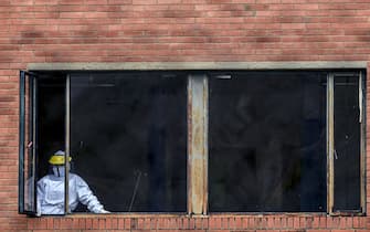 A health worker wearing a protective suit looks out from a window at a hospital for COVID-19 patients in Bogota on August 6, 2020. - More than 200,000 people have died from coronavirus in Latin America and the Caribbean, with Brazil and Mexico accounting for nearly three-quarters of those deaths, according to an AFP tally compiled last weekend from official sources. (Photo by Juan BARRETO / AFP) (Photo by JUAN BARRETO/AFP via Getty Images)