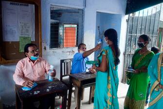 An official measures the bosy temperature of applicants before appearing to take the Uttar Pradesh Bachelor of Education entrance exam at an examination centre in Allahabad on August 9, 2020. - India's coronavirus cases passed two million on August 7 after a daily jump of more than 60,000 and around 900 new deaths, health ministry data showed. (Photo by SANJAY KANOJIA / AFP) (Photo by SANJAY KANOJIA/AFP via Getty Images)