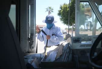 EL CENTRO, CALIFORNIA - JULY 21: A USPS postal worker wears a face mask amid the COVID-19 pandemic in hard-hit Imperial County on July 21, 2020 in El Centro, California. Imperial County currently suffers from the highest death rate and near-highest infection rate from COVID-19 in California. The rural county, which is 85 percent Latino, borders Mexico and Arizona and endures high poverty rates and air pollution while also being medically underserved. In California, Latinos make up about 39 percent of the population but account for 55 percent of confirmed coronavirus cases amid the pandemic. (Photo by Mario Tama/Getty Images)