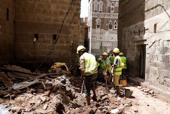 epa08599459 Yemenis work on the site of rain-collapsed buildings in the old city of Sana a, Yemen, 12 August 2020. According to reports, torrential rains and flooding in Yemen have claimed the lives of at least 170 people, including 19 children, and destroyed hundreds of houses and roads across the war-torn Arab country over the past few weeks.  EPA/YAHYA ARHAB