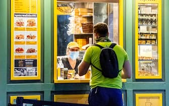 NEW YORK, NEW YORK - AUGUST 18: A server wears a mask in the Bryant Park waffle stand during the fourth phase of the coronavirus reopening on August 18, 2020 in New York, New York. The fourth phase allows outdoor arts and entertainment, sporting events without fans and media production. (Photo by Roy Rochlin/Getty Images)