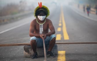 TOPSHOT - A member of the Kayapo tribe sits after they blocked highway BR163 during a protest on the outskirts of Novo Progresso in Para State, Brazil, on August 18, 2020 amid the COVID-19 novel coronavirus pandemic. - Brandishing bows and arrows, dozens of indigenous protesters blocked a main highway through the Brazilian Amazon, demanding help against the new coronavirus and an end to illegal mining and deforestation. (Photo by JOÃ O LAET / AFP) (Photo by JOAO LAET/AFP via Getty Images)