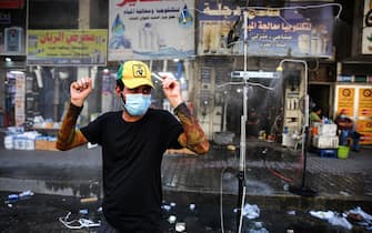 A man clad in mask due to the COVID-19 coronavirus pandemic stands next to sprinklers along Sinak street in Iraq's capital Baghdad on August 9, 2020, to cool off due to extremely high temperature rises amidst a heatwave. (Photo by AHMAD AL-RUBAYE / AFP) (Photo by AHMAD AL-RUBAYE/AFP via Getty Images)