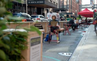 NEW YORK, NEW YORK - AUGUST 19: A man wearing a mask sits at  recently opened outdoor tables outside of Chelsea Market as the city continues Phase 4 of re-opening following restrictions imposed to slow the spread of coronavirus on August 19, 2020 in New York City. The fourth phase allows outdoor arts and entertainment, sporting events without fans and media production. (Photo by Alexi Rosenfeld/Getty Images)